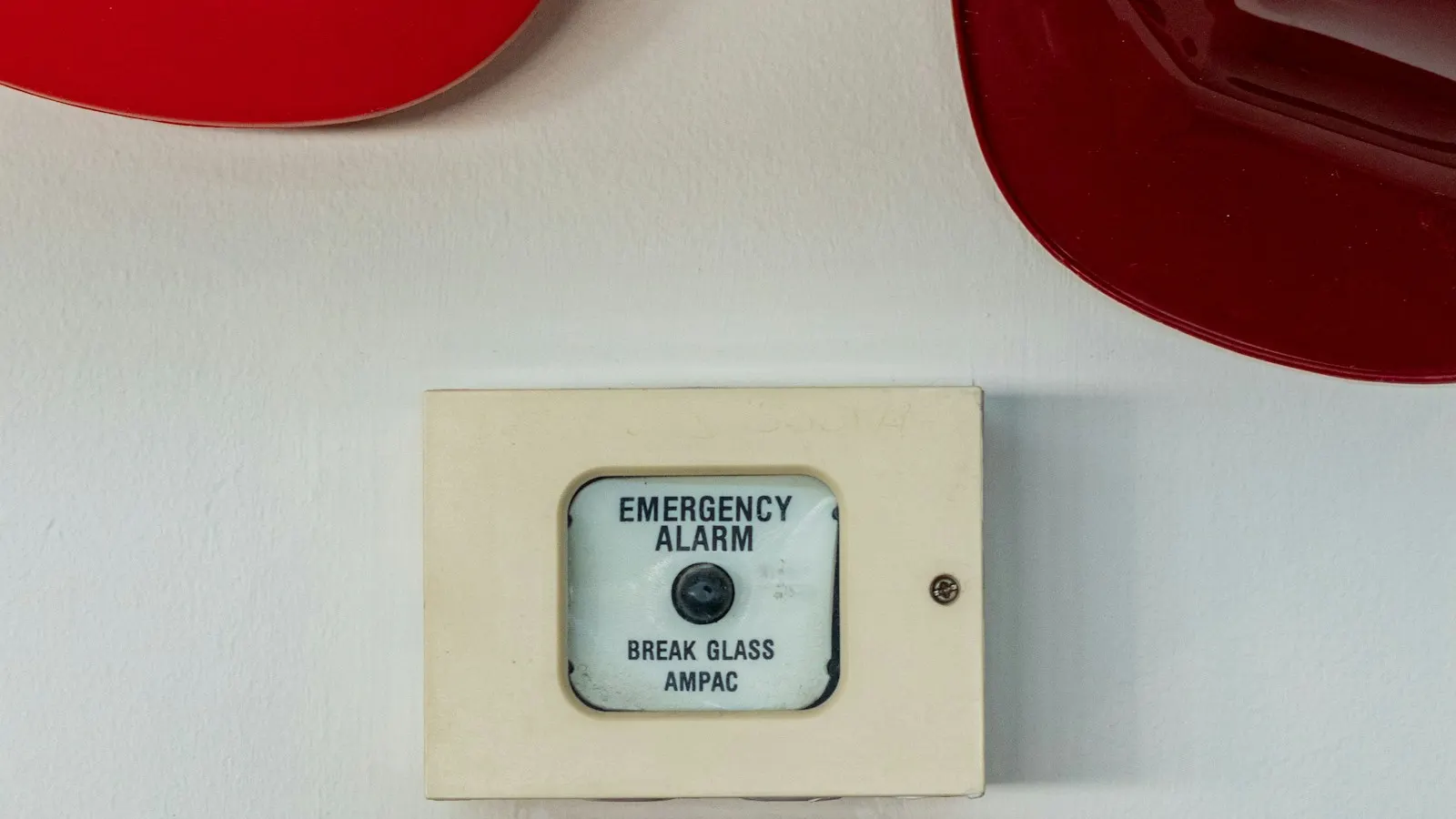 Break glass fire alarm call point on a site wall beside two red construction hard hats