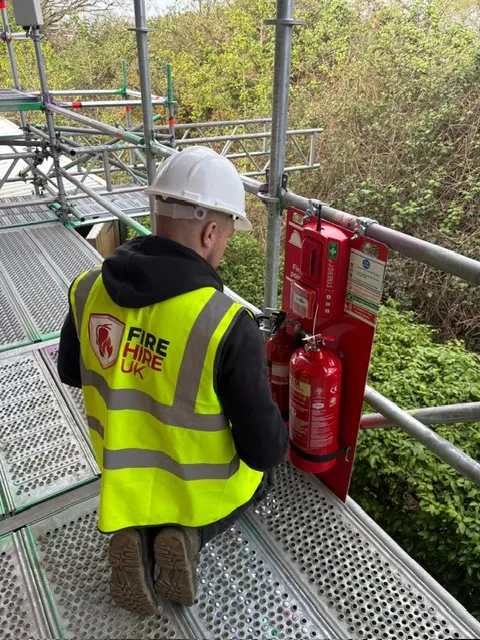Fire Hire UK engineer fitting a radio linked fire point to a scaffold