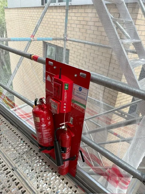 Radio linked fire point with foam and CO2 extinguishers on a scaffold beside a brick building